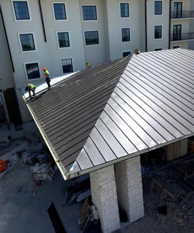 Crew installing standing seam metal roof panels on a commercial project in Griswold